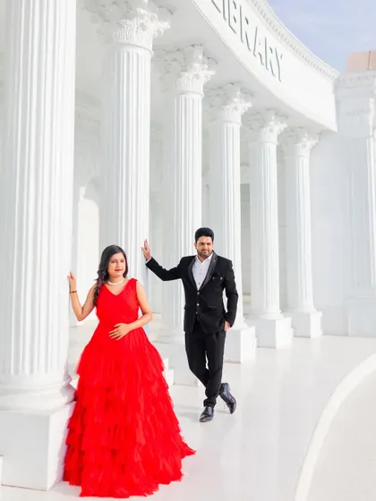A stylish portrait at a set replicating the Asiatic Library. The woman's red dress provides a striking contrast against the white pillars.