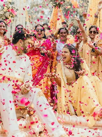 The entire family joins in the fun, showering the couple with petals during a joyous and energetic Haldi ceremony.