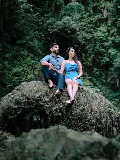 A relaxed moment during the Shimla pre-wedding shoot, with the couple sitting on a mossy rock surrounded by lush greenery.