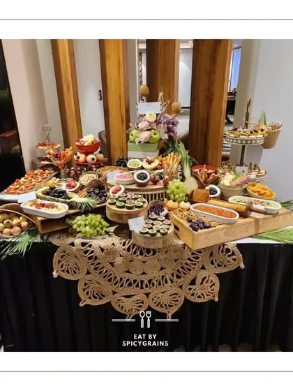 This elegant grazing table is set on a black tablecloth, making the colours of the food pop. The spread includes a variety of appetizers, from pizzas to fruit platters.