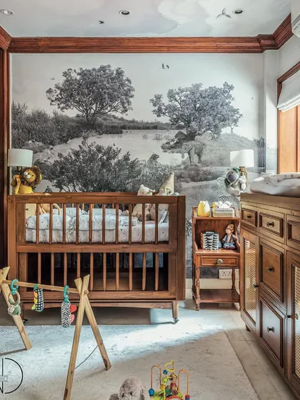 This is the other side of the nursery, featuring a serene, black and white safari-themed wallpaper. The custom teak wood crib and changing station bring a classic warmth to this calm and stylish space.