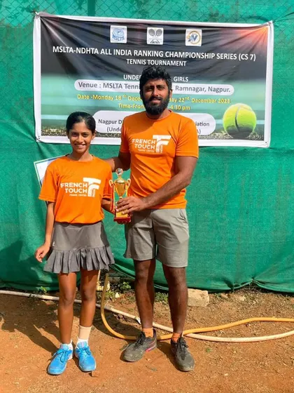 A coach and player celebrate a singles victory. Eshal Pathan with her coach and trophy after winning the All India Tennis Association Championship Series U16 tournament.