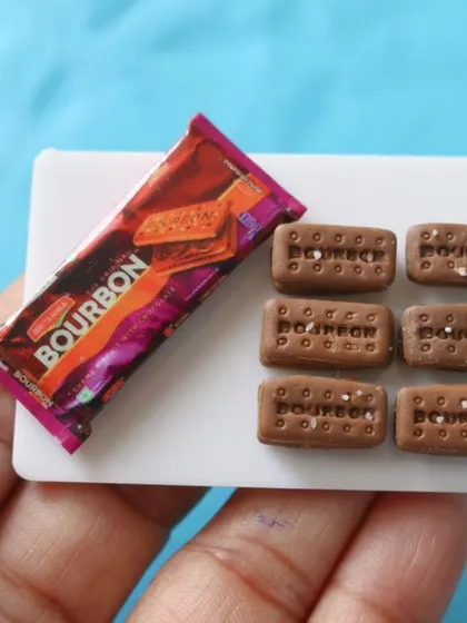 A close-up of a miniature Bourbon biscuit packet and the detailed chocolate cream biscuits.