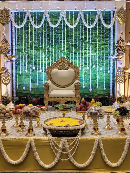 I designed this traditional baby shower stage with a lush green leaf wall and sparkling crystal hangings. The setup includes a royal chair for the mother-to-be and a fully arranged 'seer' table, creating a perfect blend of tradition and elegance for the Seemantha ceremony.