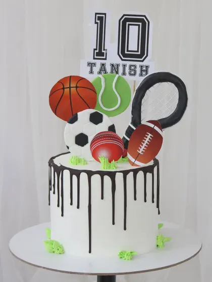 For the ultimate sports enthusiast, this cake is a grand slam. It features a clean white design with a chocolate drip and is topped with edible cutouts of a basketball, tennis ball, soccer ball, cricket ball, and more.