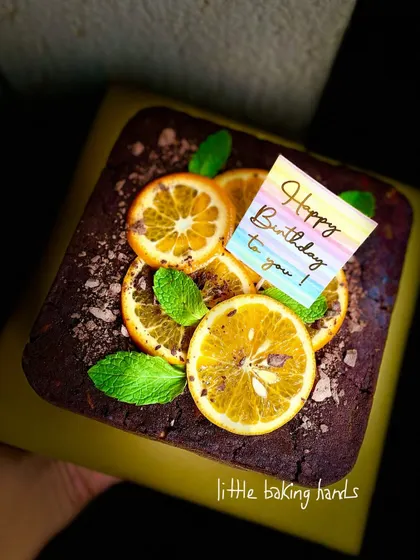 Another look at this beautiful dark chocolate orange cake, held up to show off its rich texture and fresh toppings. It's a perfect birthday treat.