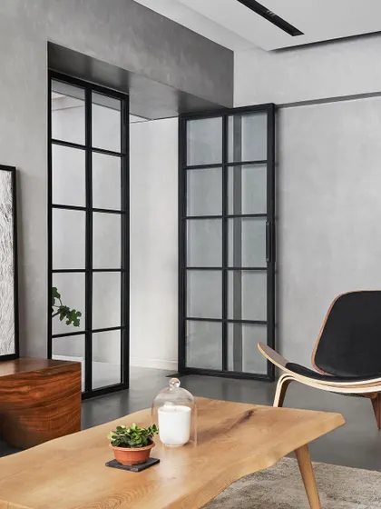 In AD House, we used black-framed glass partitions to separate spaces while maintaining a sense of openness and light. This view from the entrance into the living room frames the space like a picture.