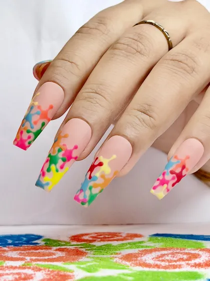 A playful Holi design with a matte nude base and colorful paint-splatter tips, a fun and trendy take on the festival.