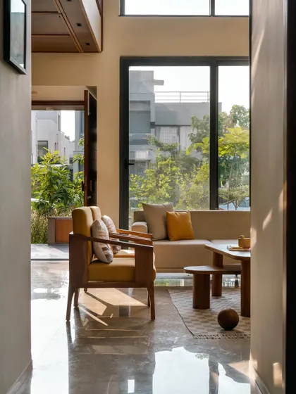 **Amber House, Ahmedabad:** Large windows connect the living space directly to the surrounding greenery, making the garden an integral part of the home. The design ensures that from every corner, you feel connected to the earthy, natural setting of the villa.
