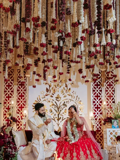 A candid moment between Naomi and Rakshit under a ceiling of hanging rajnigandha and rose garlands. This highlights the intricate floral work that created a fragrant and beautiful canopy for their ceremony.