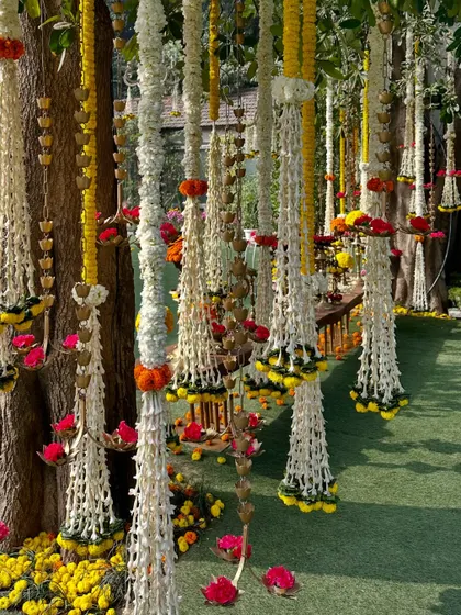 Intricate floral hangings made of tuberose and marigolds, adorning the trees and adding a touch of elegance to the outdoor setting.