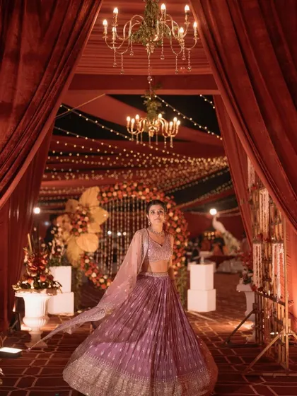 The bride making a grand entrance through a passageway of red drapes and chandeliers. This kind of dramatic entrance makes for unforgettable photos and a truly cinematic wedding moment.