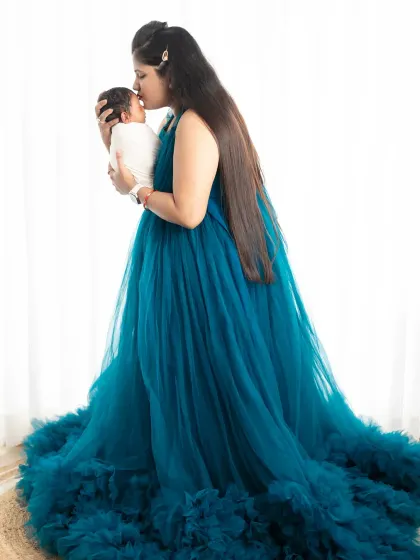 A mother in a beautiful flowing gown holds her newborn baby for the first time. This is a powerful image that connects the maternity journey with the joy of motherhood.