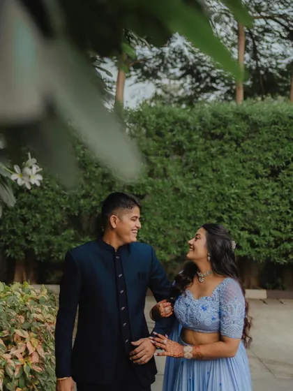 A sweet, candid moment from an engagement shoot. The couple shares a look of love as they walk through a garden, their happiness evident in their smiles.