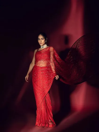 A dramatic, full-length shot where the sleek hairstyle and glowing makeup complement the flowing movement of the red saree.