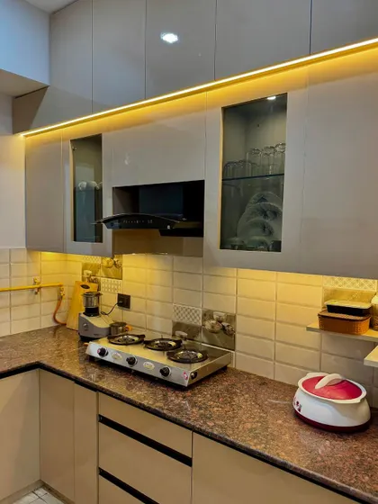 A close-up of a kitchen countertop area. The design includes beige cabinets with profile handles and fluted glass shutters for a modern look.