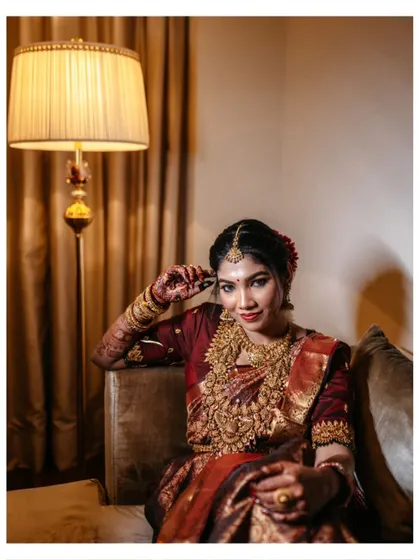 A captivating bridal portrait, with the bride seated and looking directly at the camera, her intricate jewelry and makeup on full display.