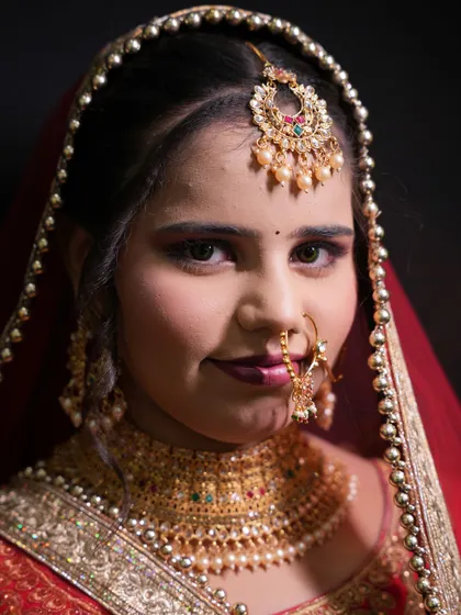 A beautiful portrait of the bride, smiling confidently. This shot highlights the complete look, from the detailed jewelry to the expertly applied makeup.