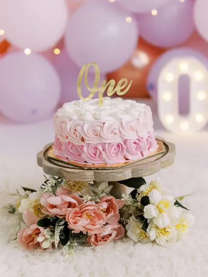 A close-up of a beautiful pink ombre cake for a first birthday smash. The details, from the cake to the flowers, are all part of the story.