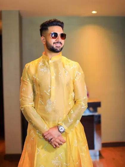 The groom, ready for his Haldi ceremony in a vibrant yellow kurta. This candid shot captures his bright smile and anticipation for the celebration.