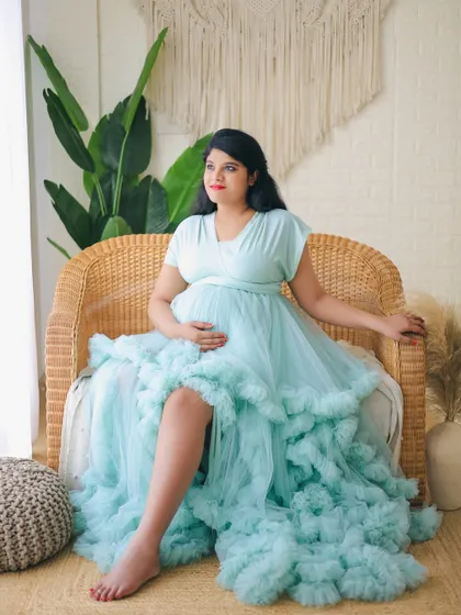 A serene portrait in a light blue ruffled gown. The client is seated in a wicker chair, part of our boho-chic studio setup, creating a relaxed yet elegant atmosphere.