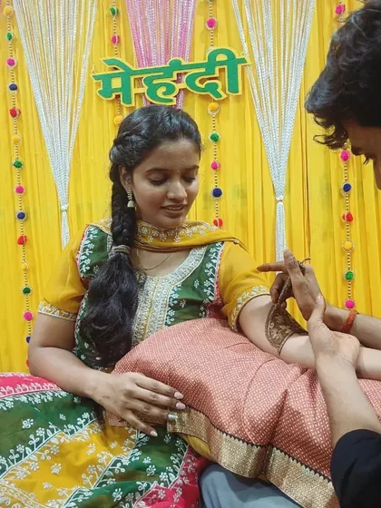 A lovely bride in a yellow and green outfit getting her mehandi done for her ceremony.