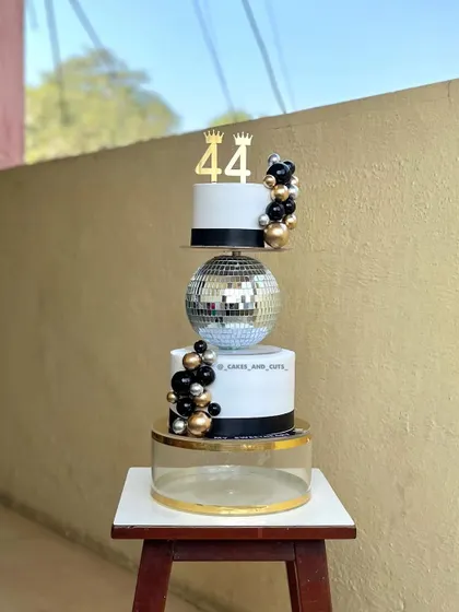 A modern and stylish 44th birthday cake featuring a disco ball tier and a black, gold, and silver color scheme. This shows how to mix textures and elements for a unique look.