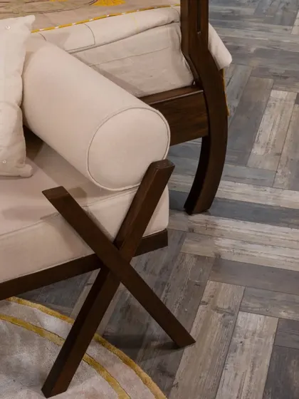 A detail shot of the four-poster bed, showing the custom-designed ottoman with its crossed wooden legs. This piece blends seamlessly with the bed frame, creating a cohesive and elegant bedroom set.