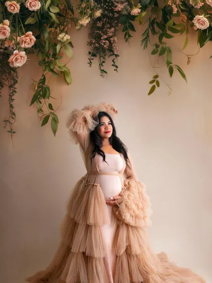 A slightly different pose in the same gorgeous setup. Her looking up towards the flowers adds a touch of whimsy and grace to this beautiful maternity photo.
