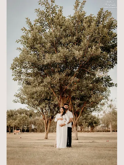 A wide shot showing the couple standing together under a large, beautiful tree. This type of environmental portrait captures not just you, but the peaceful atmosphere of the day.
