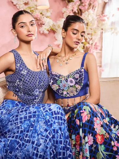 A close-up of two models for Krisha Sunny Ramani. This shot highlights the detailed makeup, from the soft shimmer on the eyes to the flawless skin, complementing the intricate blue outfits.