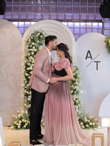 A tender moment between the parents-to-be, captured in front of the beautiful white floral backdrop.