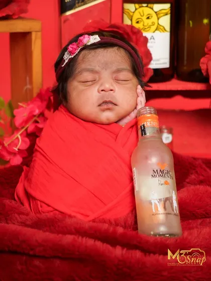 A fun and playful "Magic Moments" theme. This creative setup uses bottles and a red color scheme for a unique and humorous newborn photo.