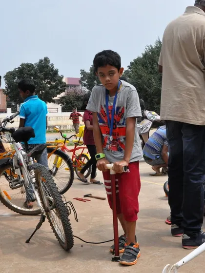 A young boy confidently uses a pump to inflate a bicycle tire. We empower kids to take charge of their own bike maintenance, building their skills and independence.