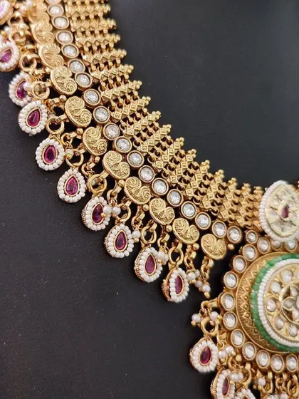 A close-up of a temple-style necklace for rent. The detailed craftsmanship on the gold-tone coins and the use of colored stones are highlighted here.