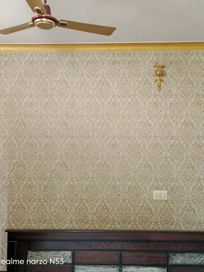A classic damask wallpaper in gold and beige, installed in a bedroom.