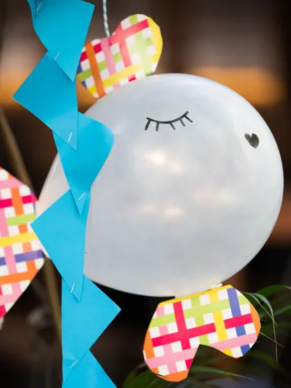 Even balloons get a themed makeover! This simple white balloon is transformed into a cute fish with paper fins and a hand-drawn face, showing how creative details can enhance the party's theme.