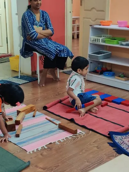 A parent observes her child working with Montessori materials. These sessions are a powerful way for parents to connect with their child's school experience and understand their learning journey.