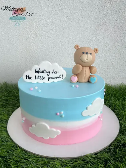"Waiting for the little peanut!" This cute teddy bear cake is perfect for a gender-neutral baby shower. The pink and blue ombre frosting is decorated with fondant clouds and a sweet message.