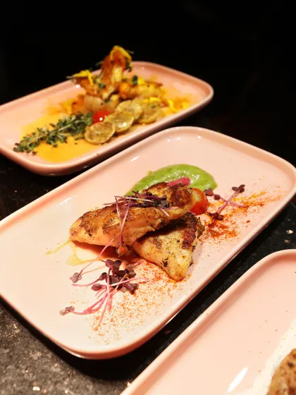 An example from our "Flames of the Orient" menu. This Pan-Asian dish features perfectly grilled chicken on a contemporary pink plate, garnished with micro-herbs and a sprinkle of spice, showcasing a fusion of flavour and style.