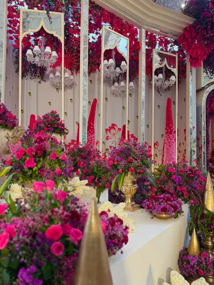 A decor corner filled with an abundance of flowers in bold hues. The mirrored panels and traditional golden elements add layers of luxury and glamour.