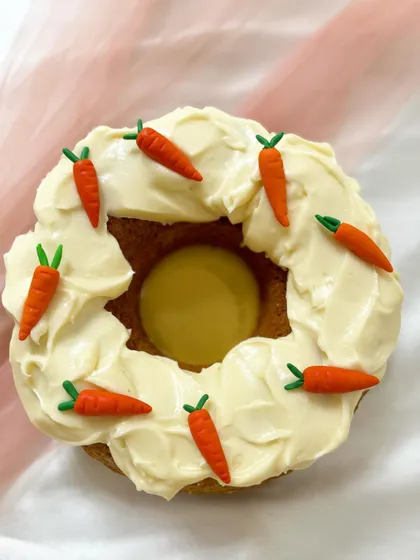 A mini cake that looks like a donut. This carrot cake is topped with cream cheese frosting and tiny, handcrafted fondant carrots.