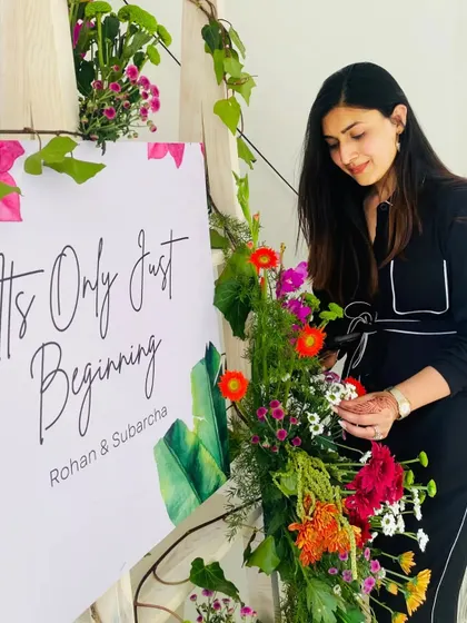 It's only just beginning. A beautiful welcome sign adorned with fresh, vibrant flowers, with me adding the final touches. This is the kind of personal detail I love to create.