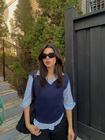A preppy, layered look with a sweater vest over a button-down shirt.