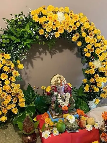 A bright and sunny Ganpati decoration featuring a circular arch of yellow roses and chrysanthemums. This cheerful design is perfect for welcoming Bappa with joy and positivity.