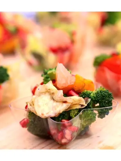 A close-up of a vegan and gluten-free appetizer cup, featuring fresh broccoli, pomegranate, and citrus, demonstrating our commitment to catering for all dietary needs.