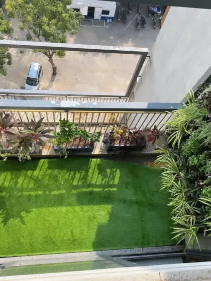 An aerial view of a balcony transformation. The artificial grass completely covers the floor, providing a clean, uniform look that is both practical and visually appealing.