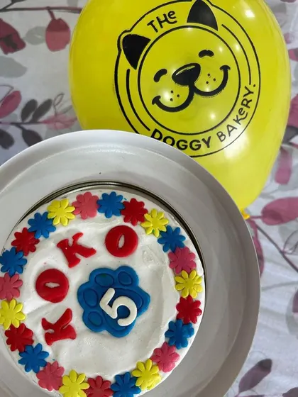 A close-up of Koko's colorful Flower Power cake, complete with his name and age. We also include our branded balloons to add to the festive atmosphere.