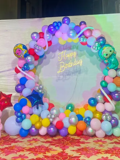 A slightly different view of the colorful Cocomelon balloon ring, highlighting the placement of the character and star-shaped foil balloons.