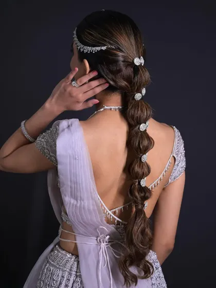 A detailed back view of the accessorized bubble braid. This bridal hairstyle is all about making a statement, and the accessories add a layer of luxury and intricacy.